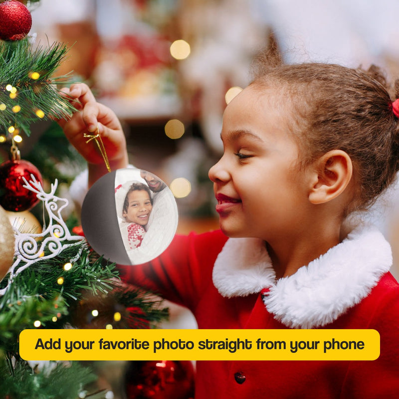 Child hanging Video Memory Christmas Tree Ornament displaying family photo on decorated tree